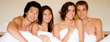 Two Swinging couples sitting naked In A Bed
